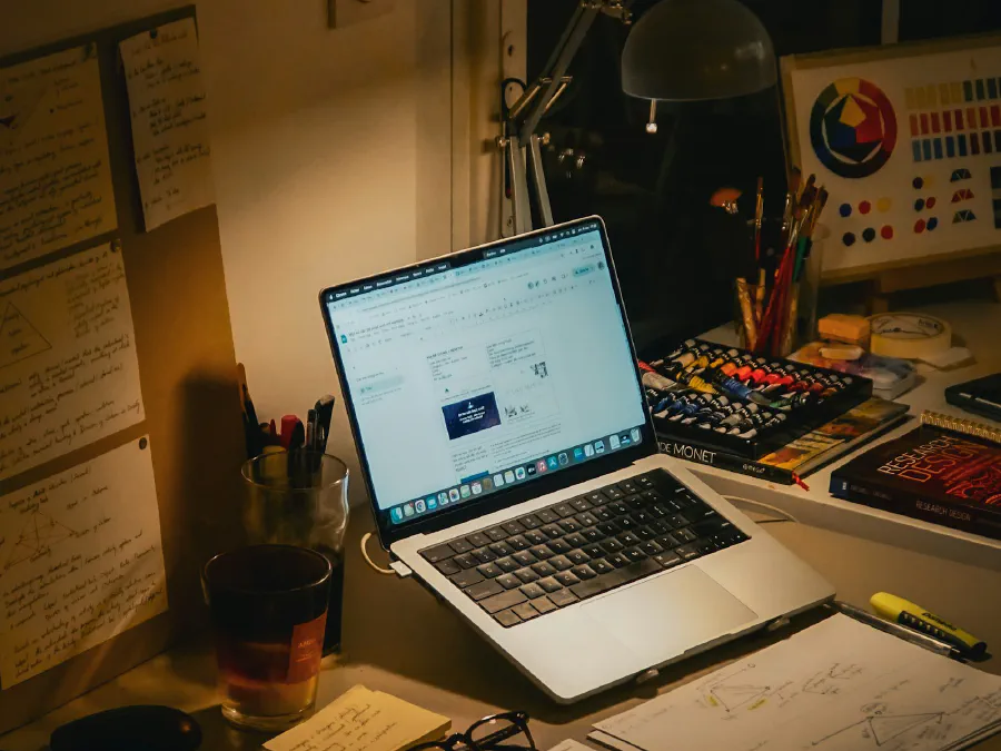 Laptop on a desk with notebooks and papers
